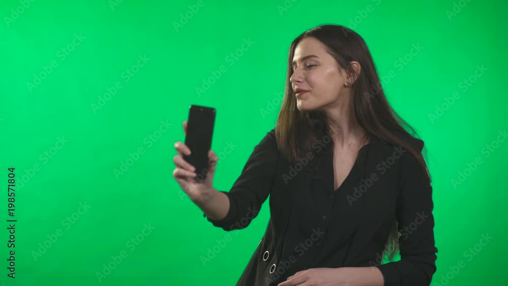 Girl take a selfie on smartphone, photographs herself, on green background. Girl take a selfie on smartphone, photographs herself, on green background.