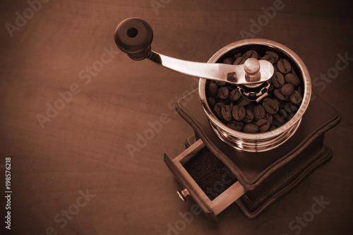 Old coffee grinder with coffee beans on wooden table with space for text