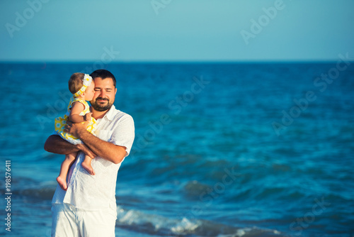 Happy father playing with cute little daughter at the beach