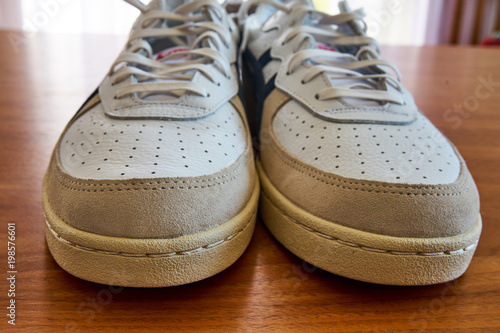 Front View Of A Pair Of Vintage White Sneaker Shoes On A Wooden Surface
