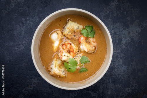 Traditional French fish soup with prawns and croutons at top view in a bowl photo