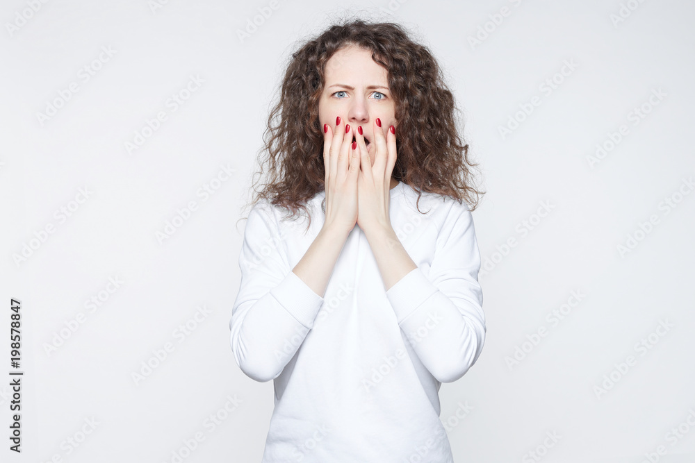 Reaction of young Caucasian woman at a global tragedy, bad news at television. Shocked casually dressed lady can’t imagine and believe in what happened. Negative emotions and expressions concept. Reaction of young Caucasian woman at a global tragedy, bad news at television. Shocked casually dressed lady can’t imagine and believe in what happened. Negative emotions and expressions concept.