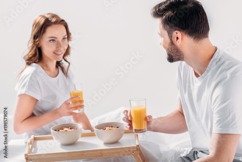 young couple having breakfast in bed in morning together isolated on grey