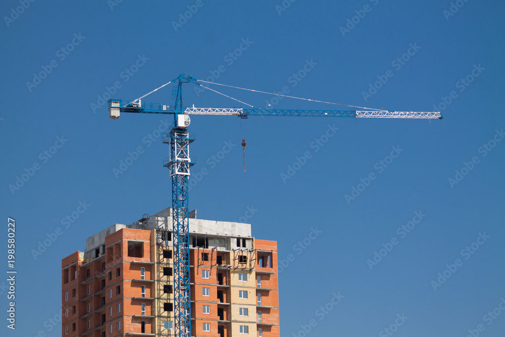 tower crane on a construction site on the blue sky background tower crane on a construction site on the blue sky background