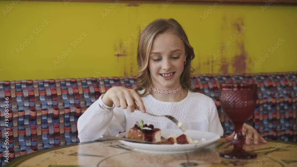 Pretty young girl eating tasty dessert and looking at window. 4K