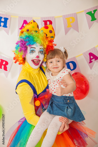 clown girl on the birthday of a child. A party for a child. Keep the baby in your arms