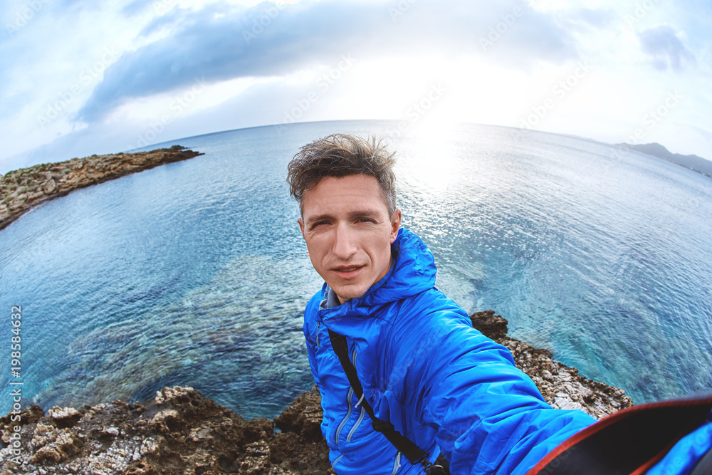 Fototapeta premium young man in blue jacket make selfie photo on the beach at sunset