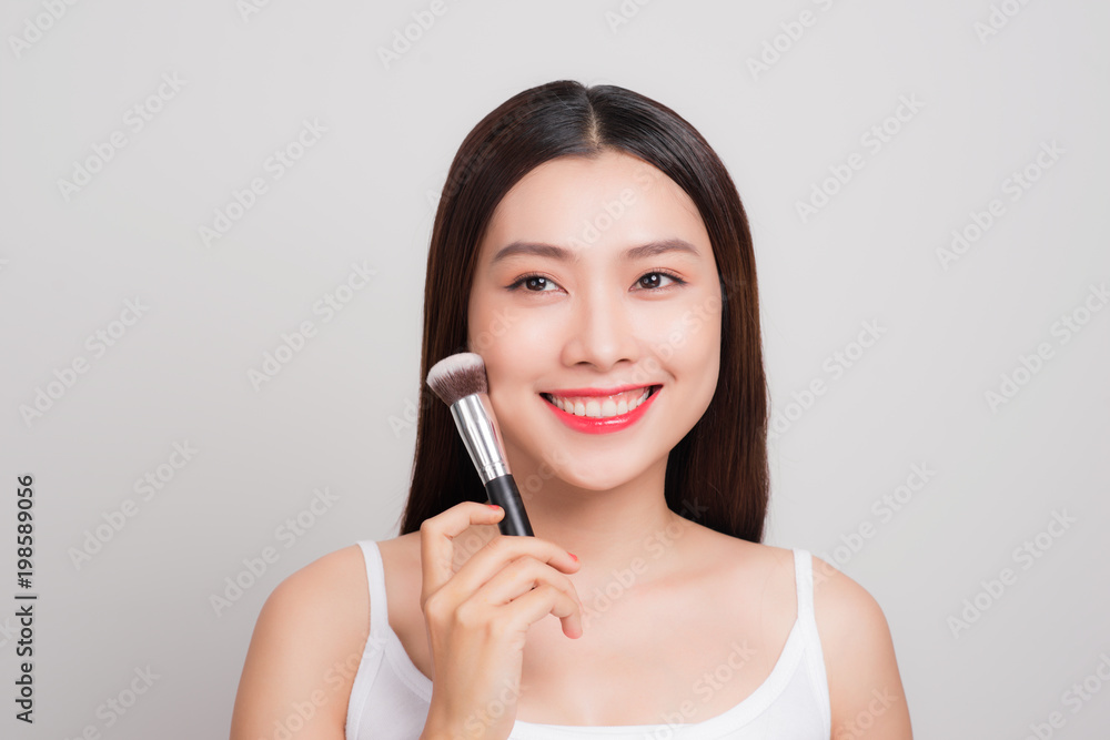 Portrait of attractive young asian woman holding make-up brushs over white Portrait of attractive young asian woman holding make-up brushs over white