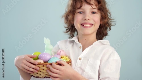 Happy easter. A schoolboy with an Easter basket smiling cheerfully. Portrait on a blue background photo