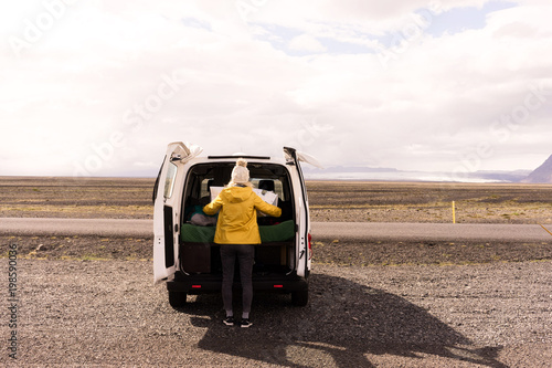 Woman looking at a map on the back of a camper van