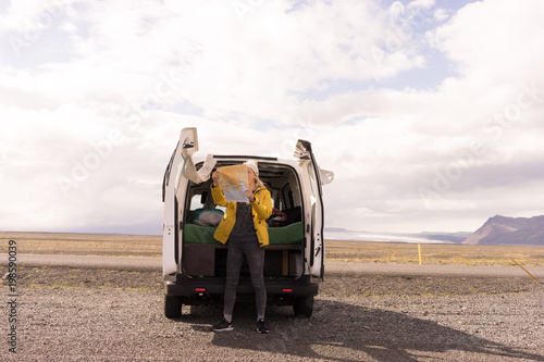 Woman standing by van looking at a map