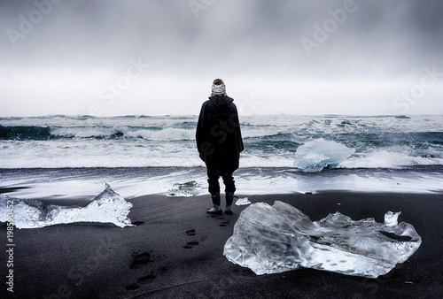 Woman looking out to sea with ice and black sand photo