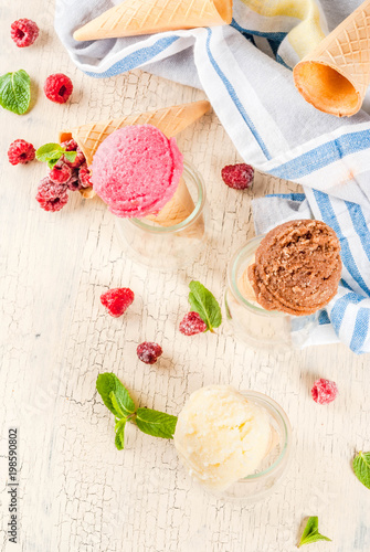 Summer sweet berries and desserts, various of ice cream flavor in cones pink (raspberry), vanilla and chocolate with mint on light concrete background copy space
