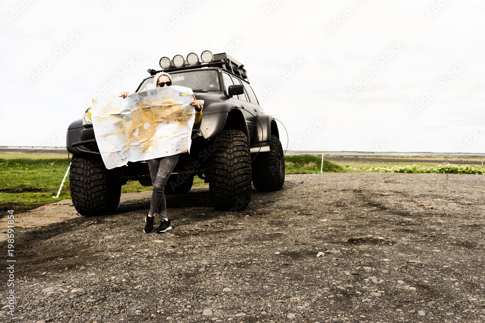 Fototapeta premium Woman Leaning on 4x4 truck reading map
