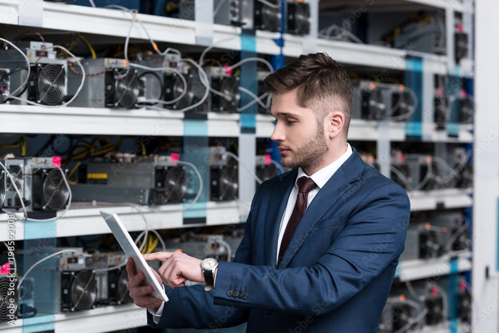 serious young businessman using tablet at ethereum mining farm serious young businessman using tablet at ethereum mining farm