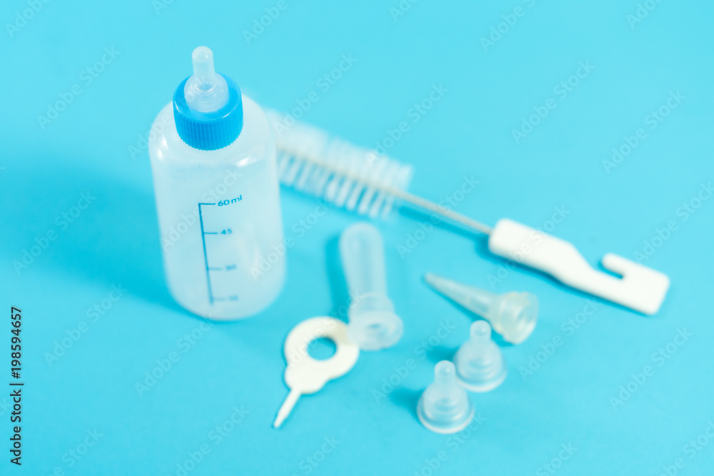 Fototapeta premium Pet accessories concept: Bottle feeding for pet and cleansing tools on blue background.