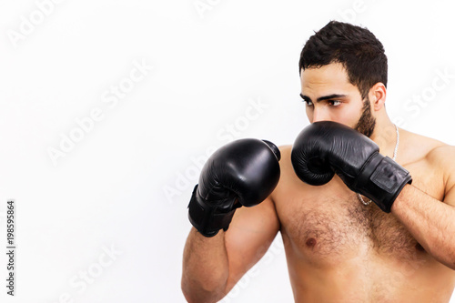 Muscular handsome topless boxer wears black gloves ready to fight before white background