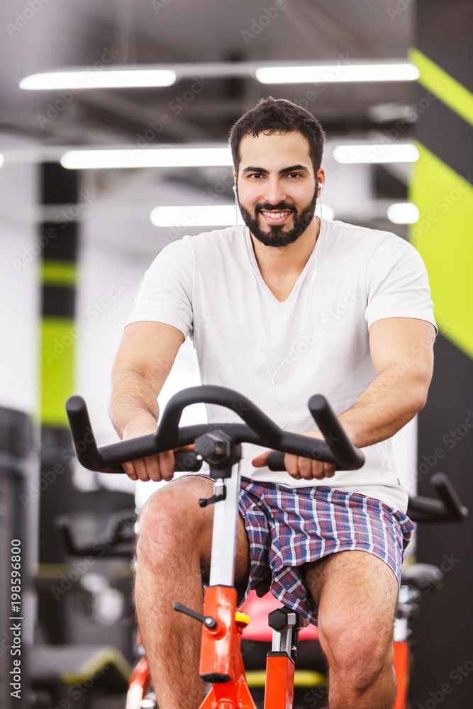 Muscular man cycling on exercise bike in the gym Muscular man cycling on exercise bike in the gym