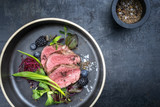 Traditional barbecue aged sliced fillet steak with wild garlic and fruits top view on a plate with copy space