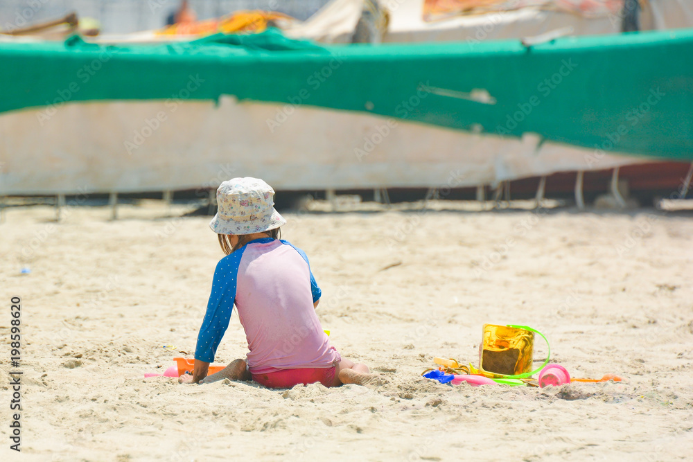 Little girl playing in the sand on Mandrem beach in North Goa.India Little girl playing in the sand on Mandrem beach in North Goa.India