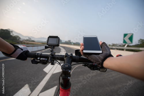 Cyclist using smartphone for navigation when riding mountain bike on highway