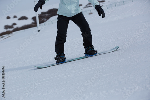 snowboarder descent on winter ski resort slope