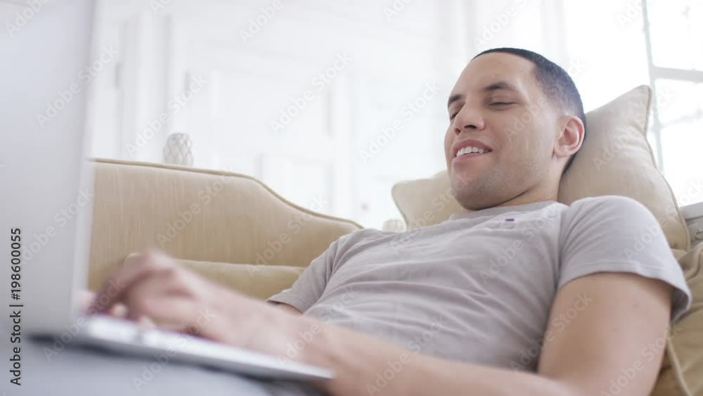 Handheld shot of handsome male on his laptop at home Handheld shot of handsome male on his laptop at home