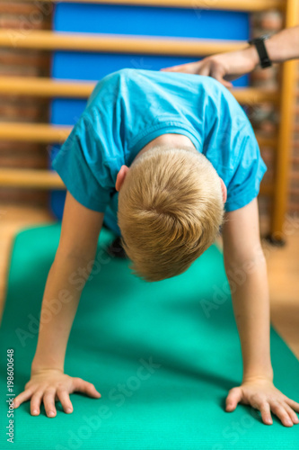 Kind bei der Kinderphysiotherapie macht einen Liegestütz auf einer Gymnastikmatte und hält den Rücken dabei gerade