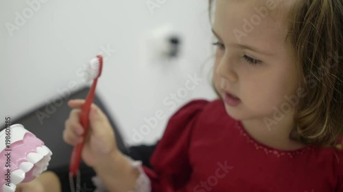 Child girl cleaning teeth jaw in medical dental clinic with tooth brush photo