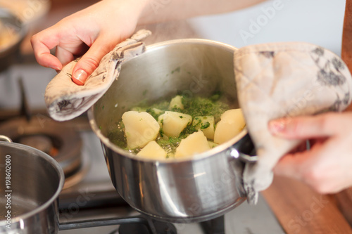 Cook holds pan with boiled potatoes