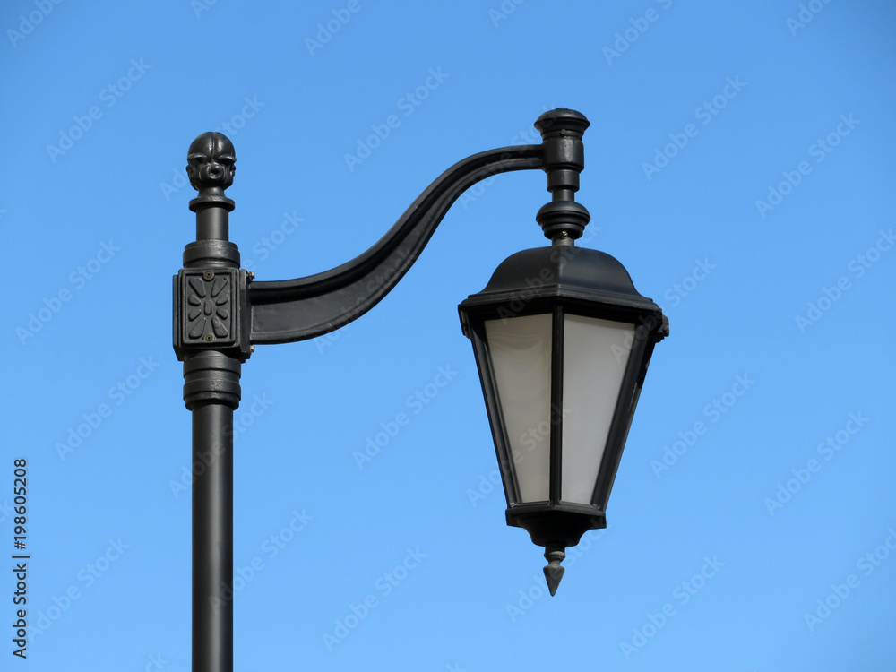 Vintage iron street lamp isolated. City street lantern on the background of clear blue sky 