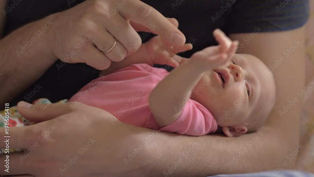 Close-up shot of newborn baby girl in strong fathers hands, child touching and catching dads fingers. Touching moments of parenthood Close-up shot of newborn baby girl in strong fathers hands, child touching and catching dads fingers. Touching moments of parenthood