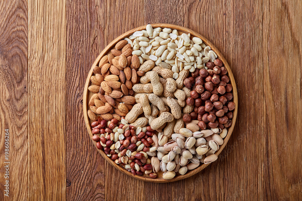 Mixed nuts arrenged on wooden tray over rustic background, close-up, selective focus. Mixed nuts arrenged on wooden tray over rustic background, close-up, selective focus.