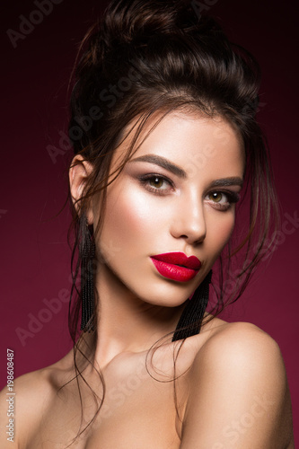 Gorgeous Young Brunette Woman face portrait. Beauty Model Girl with bright eyebrows  perfect make-up  red lips  touching her face. Sexy lady makeup for party.