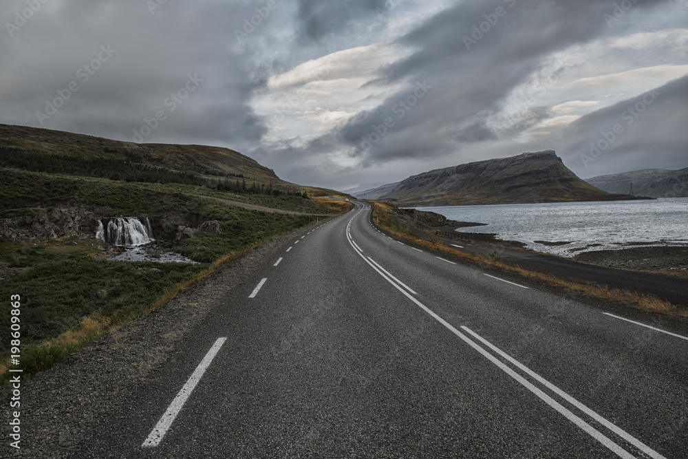 a deserted asphalt road running away into the hills, along the road a waterfall. Iceland. The spirit of travel and adventure.
a deserted asphalt road running away into the hills, along the road a waterfall. Iceland. The spirit of travel and adventure.