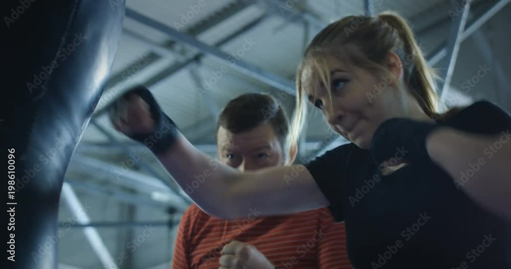 Brutal bearded man helping young sportswoman with boxing techniques training on ring. Brutal bearded man helping young sportswoman with boxing techniques training on ring.
