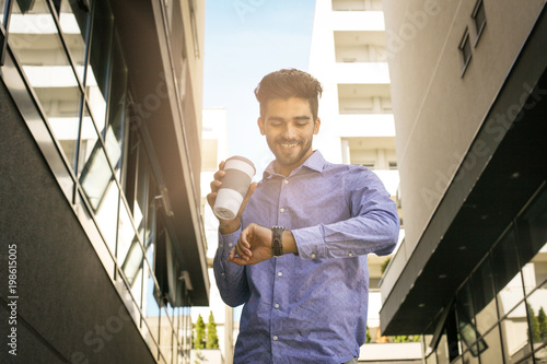 Activity businessman walking trough street checking the time.