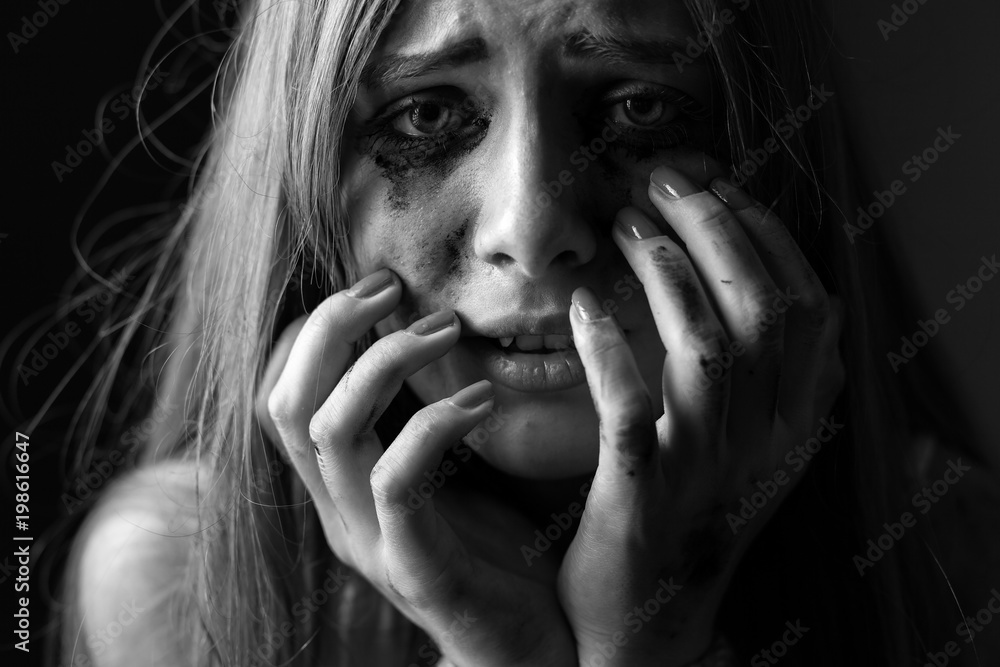 Crying young woman on a black background. Closeup. Black and white. Shallow depth of field Crying young woman on a black background. Closeup. Black and white. Shallow depth of field