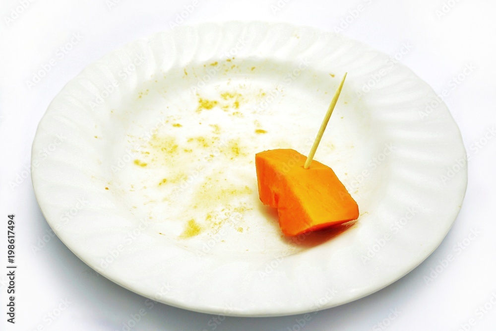 Delicious sweet papaya, the last piece with small stick (ready to pick) on a white plate, isolated on white background. Healthy and high fibre fruit; rich sources of antioxidant nutrients. Delicious sweet papaya, the last piece with small stick (ready to pick) on a white plate, isolated on white background. Healthy and high fibre fruit; rich sources of antioxidant nutrients.