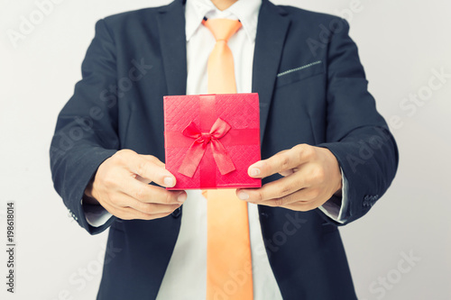 Businessman holds out the gift red box, isolated background