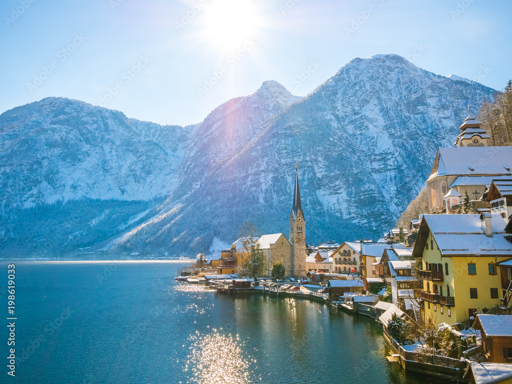 Classic postcard view of famous Hallstatt lakeside town in the Alps moutain ship on a beautiful cold sunny day with blue sky and clouds in winter, Salzkammergut region, Austria