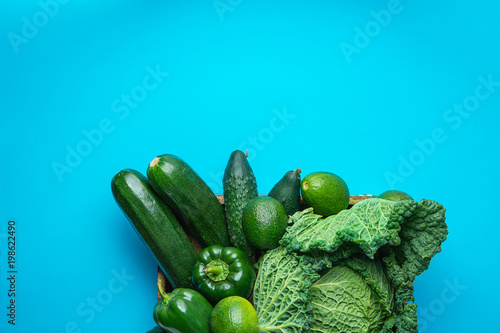 Tray with Fresh Organic Green Vegetables Savoy Cabbage Zucchini Cucumbers Bell Peppers Avocados on Bright Blue Background. Superfoods Vegan Plant Based Diet Concept. Copy Space