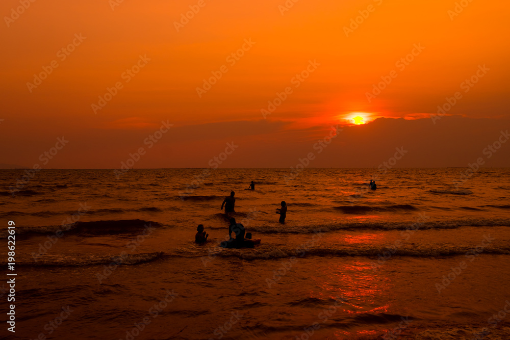 People are swimming in the sea, relaxing. At sunset