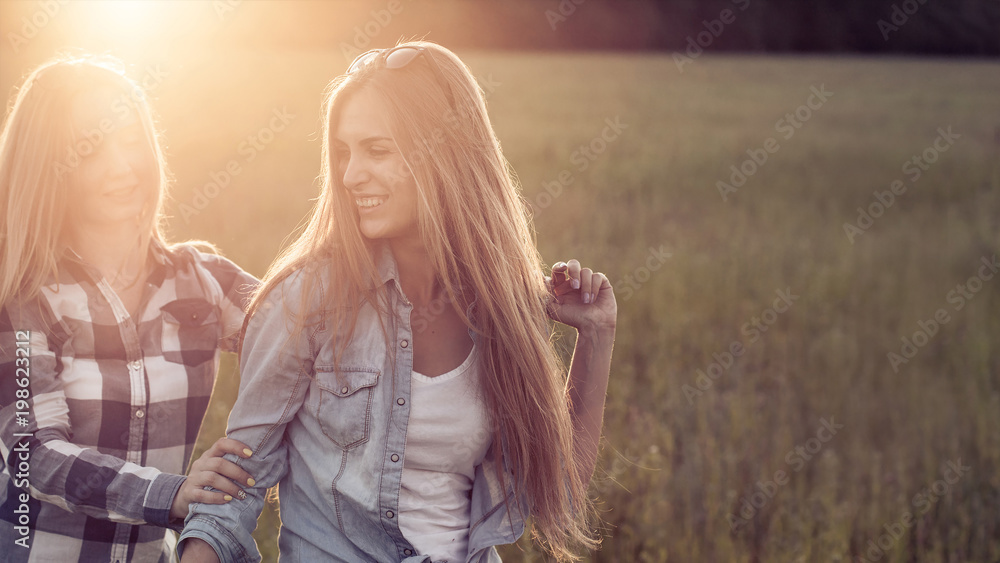 Naklejka premium Two young women walking at sunset