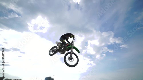 Racer on a motorcycle in flight, jumps and takes off on a springboard against the sky. Concept active extreme rest. Slow motion