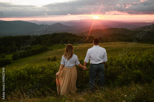Couple Holding Hands on a Mountain Watching the Sunset