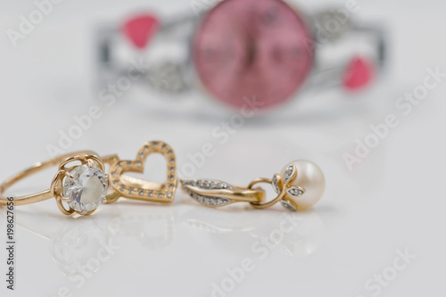 Gold earrings in the shape of a heart on a background of elegant women's watches