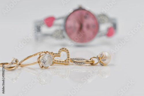 Gold earrings in the shape of a heart on a background of elegant women's watches