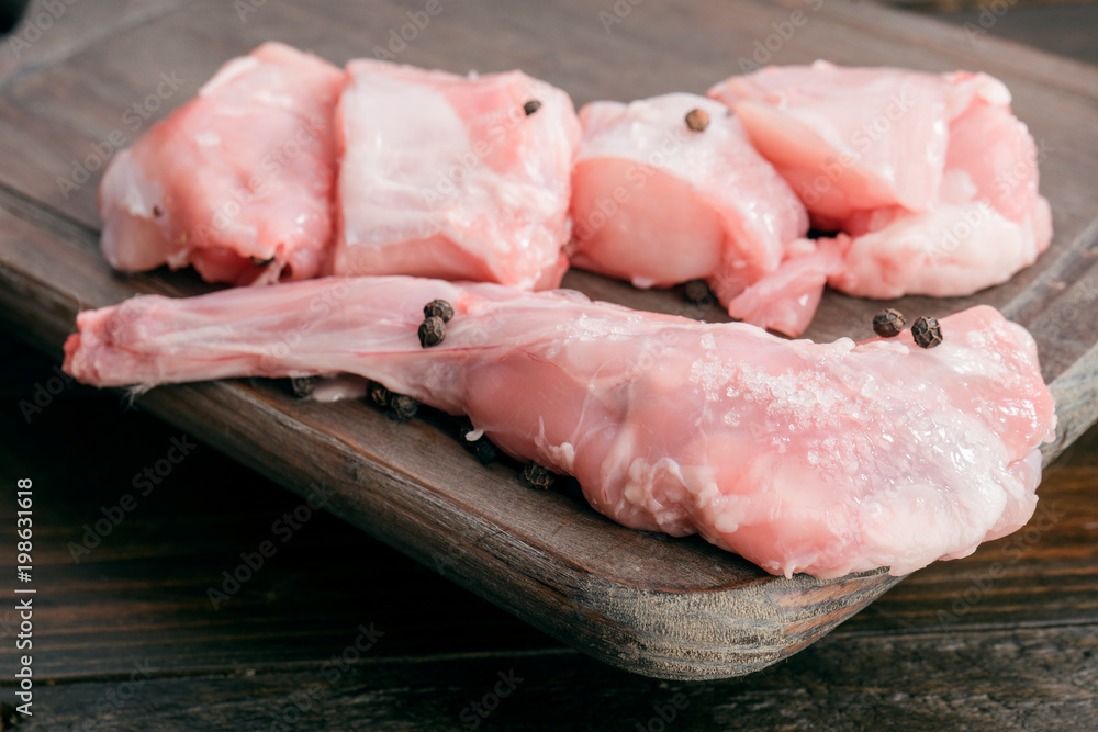 Raw chopped rabbit with salt and pepper on wood