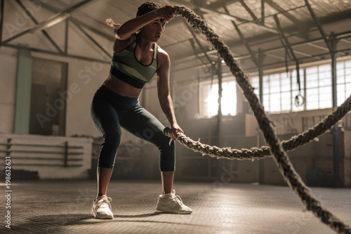 Athlete working out with battle ropes at cross gym